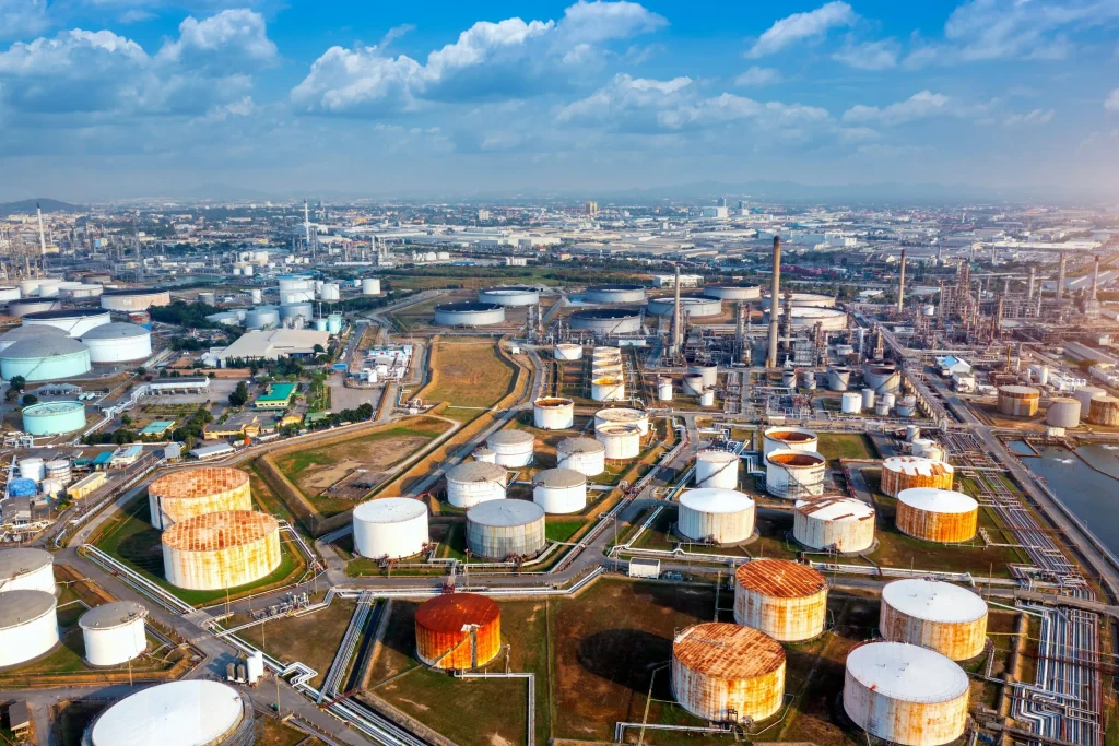 Aerial view of gas and oil refinery with storage tanks and industrial infrastructure under a clear sky