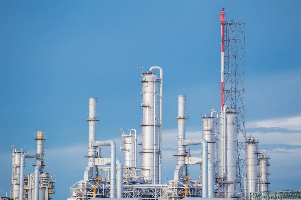 Modern oil refinery with distillation towers under a clear blue sky during daytime operations